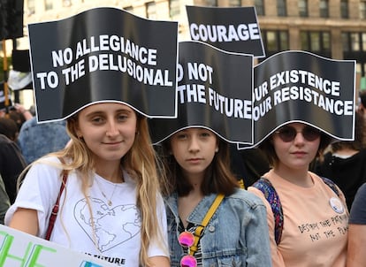 Tres jóvenes con pancartas contra el cambio climático participan en la marcha de Nueva York, EE.UU. 