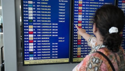 Una pasajera consulta la pantalla de informacion de vuelos.
