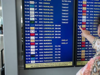 Una pasajera consulta la pantalla de informacion de vuelos.