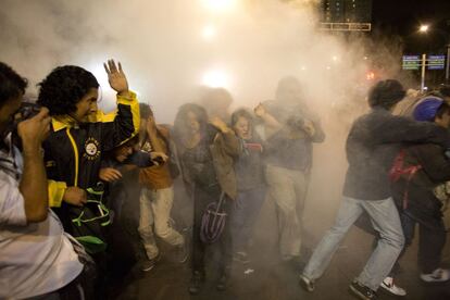 La gente huye por el humo de los extintores disparado por la policía, que trataba de contener a aquellos que estaban provocando los disturbios.