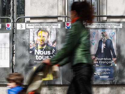 Una mujer pasaba el lunes junto a dos carteles electorales de Emmanuel Macron y Marine Le Pen, en París.