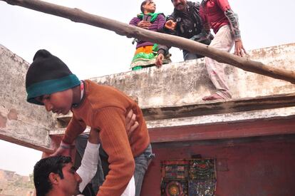 Trabajadores de una ONG local y de la unidad Anti-Tráfico ayudan a un grupo de niños rescatados de un taller de Jaipur a bajar del tejado donde corrían a esconderse.