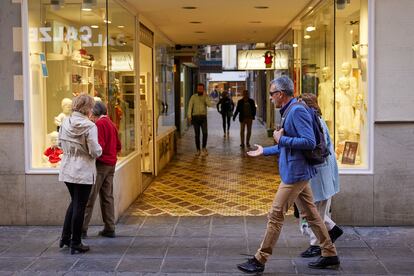 Viandantes pasan junto a una galería comercial en una calle del centro de Granada.