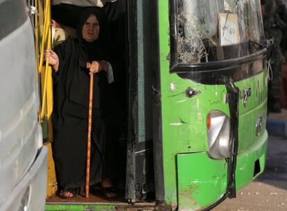 Una mujer baja del autobús a su llegada al campamento de Alepo.