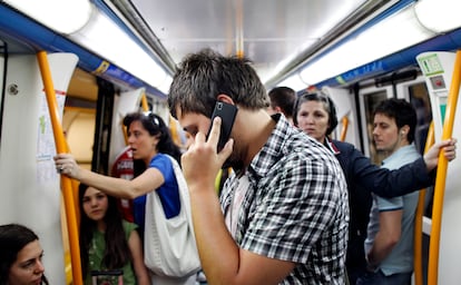 Un usuario habla por el móvil en un vagón del metro de Madrid.