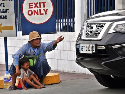 Un hombre y su hijo pequeño piden limosna en la salida de un centro comercial, en el distrito de Parañaque, en Metro Manila, Filipinas.