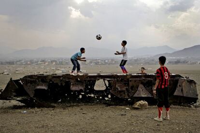 Niños afganos juegan al fútbol a las afueras de Kabul, encaramados a los restos de un carro de combate ruso, el 6 de octubre de 2011.