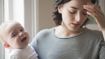 Una madre agotada con su bebé llorando.