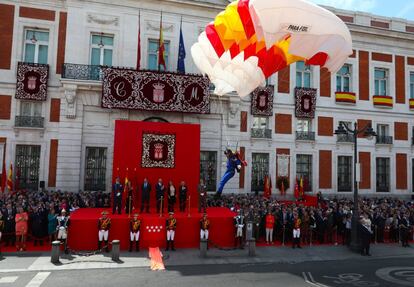 Un paracaidista desciende frente a la Real Casa de Correos antes del desfile.