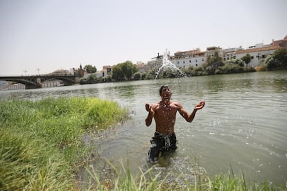 Un joven se refresca en el río Guadalquivir a su paso por Sevilla.