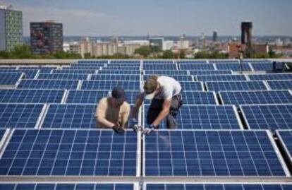 Fotografa que muestra dos operarios instalando un panel solar en el techo de la universidad de Dresde (Alemania). EFE/Archivo