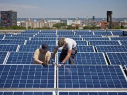 Fotografía que muestra dos operarios instalando un panel solar en el techo de la universidad de Dresde (Alemania). EFE/Archivo