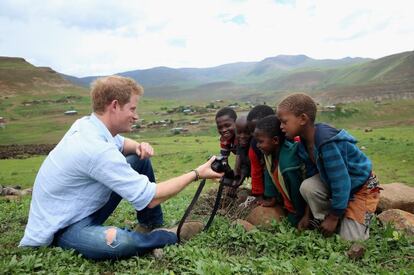 El príncipe Enrique de Inglaterra juega con unos niños y una cámara de fotos en una visita a una escuela construida en Mokhotlong, Lesotho gracias a su ONG Sentebale, el 8 de diciembre de 2014.
