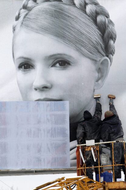Empleados municipales tapan el cartel de Timoshenko, ayer en Kiev.