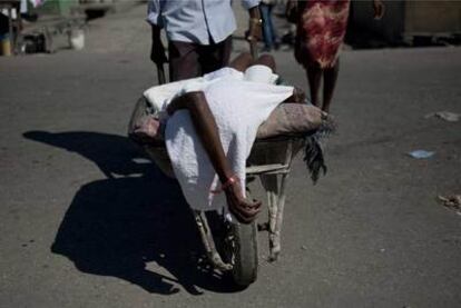 Una persona con síntomas de cólera es transportada al hospital en una carretilla en Puerto Príncipe.