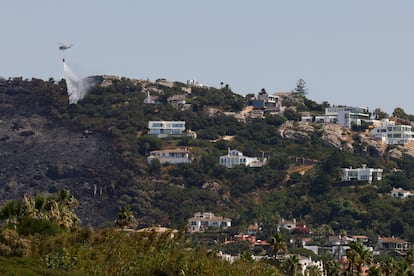 Un helicóptero refresca el flanco del incendio que se ha quedado a las puertas de las lujosas villas de Atlanterra, en la zona cercana a la playa de los Alemanes, en Tarifa