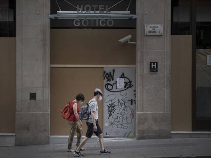 Uns turistes davant d'un hotel tancat al barri Gòtic de Barcelona.