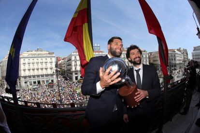 Los jugadores del Real Madrid Baloncesto Felipe Reyes y Sergio Llull posan con el trofeo de campeones ante los aficionados desde el balcón de la Real Casa de Correos.