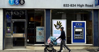 Una pareja camina junto a una sucursal del banco británico TSB en Londres.