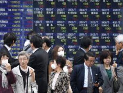 Viandantes caminan frente a una pantalla que muestra los valores de las acciones de la Bolsa de Tokio. EFE/Archivo