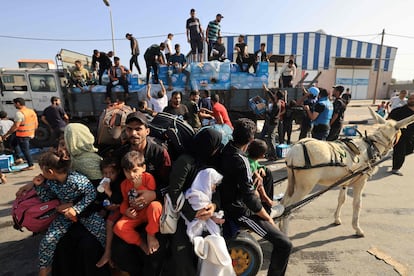 Un camión con ayuda humanitaria es descargado mientras una familia huye de la ciudad de Gaza, este jueves.