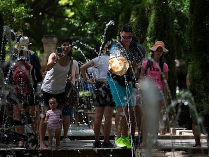 Varios turistas se refrescan en las fuentes cercanas al Palacio de la Almudaina, en Palma de Mallorca, este martes.
