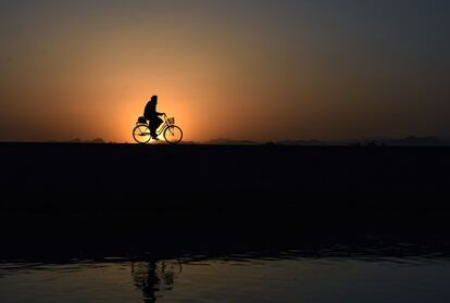 Un hombre circula con su bicicleta a lo largo de una carretera al atardecer, en la provincia de Kandahar (Afganistán).
