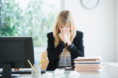 Businesswoman blowing nose in office