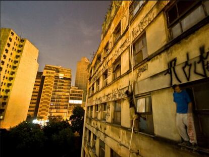 Dos jóvenes encaramados a una cornisa para pintar en un edificio de Sao Paulo.