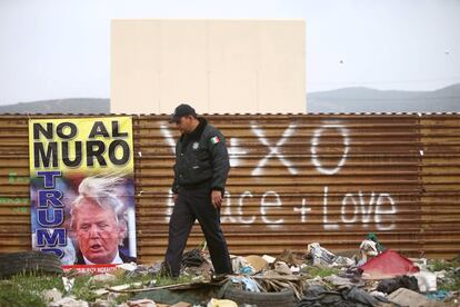 Un policía federal mexicano pasea frente a un cartel de protesta por el muro de Donald Trump en Tijuana (México), el 13 de marzo.