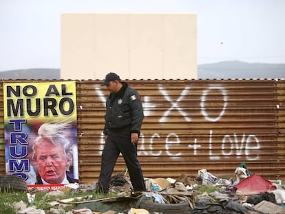 Un policía federal mexicano pasea frente a un cartel de protesta por el muro de Donald Trump en Tijuana (México), el 13 de marzo.