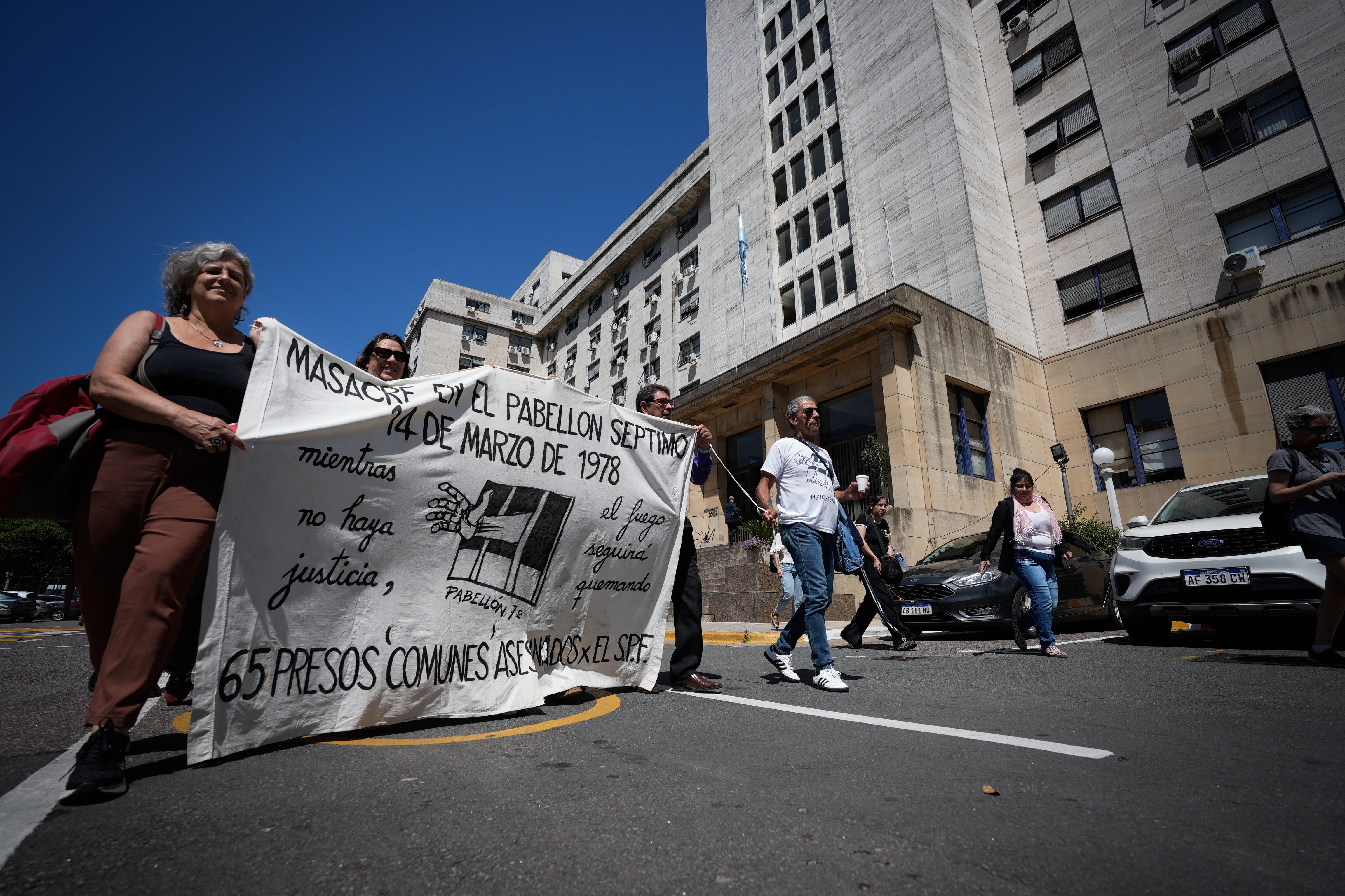 Asistentes a la lectura del veredicto ingresan con una bandera a los tribunales de Comodoro, este jueves.