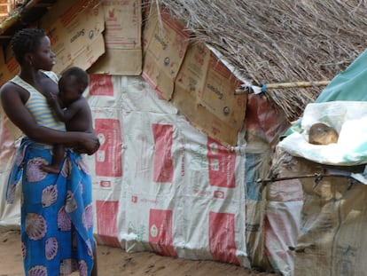 Una mujer coge en brazos a su hijo en el campo de desplazados de Maringanha. Detrás, la precaria casa en la que viven.