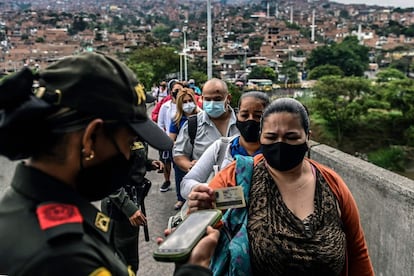 Una policía comprueba una identificación para confirmar la autorización para estar fuera, como medida preventiva contra la propagación de la covid-19, en la entrada de una estación de metro en Medellín (Colombia).