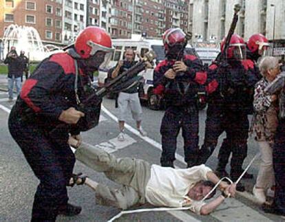 Varios <i>ertzainas</i> intentan detener a uno de los participantes en la manifestación de ayer en Bilbao.