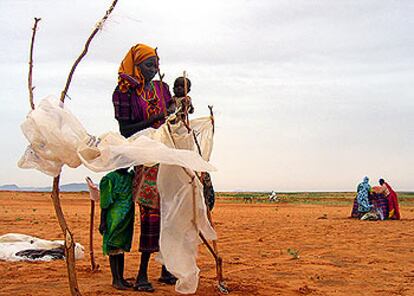 Hawa, una refugiada del campo de desplazados de Abu Shouk, en Darfur, trata de rehacer el refugio de plástico que la lluvia destrozó por la noche.