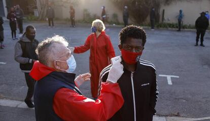 Un voluntario toma la temperatura en una cola durante el reparto de comida en una iglesia de Johannesburgo (Sudáfrica).