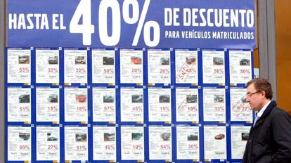 Un concesionario de vehículos con un cartel anunciando grandes decuentos por la compra de turismos y todoterrenos.