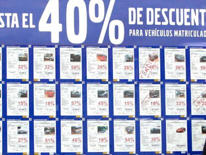 Un concesionario de vehículos con un cartel anunciando grandes decuentos por la compra de turismos y todoterrenos. 