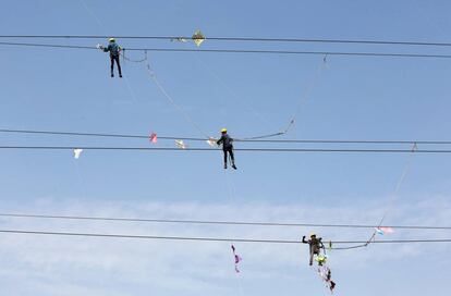 Varios trabajadores de una compañía eléctrica eliminan cometas enredadas en cables de alta tensión, en Ahmedabad (India).