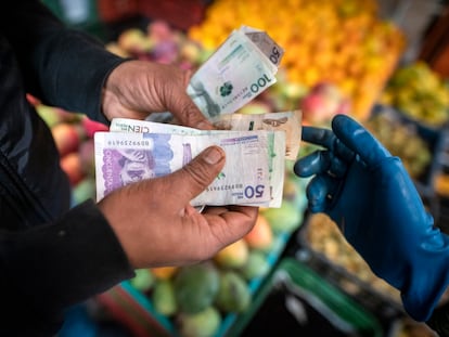 Un comprador paga por productos agrícolas en un mercado de alimentos en Bogotá, Colombia.