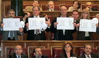 Un grupo de diputados de IU sostiene carteles contra la nueva ley durante la sesión en el Congreso.