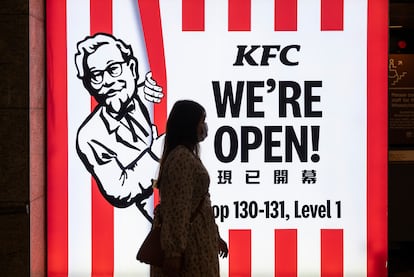 Una mujer camina por delante de un restaurante de la cadena estadounidense KFC  en Hong Kong.