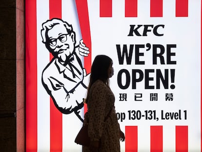 Una mujer camina por delante de un restaurante de la cadena estadounidense KFC  en Hong Kong.