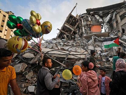 Un hombre palestino vende globos frente a un edificio destruido por los ataques aéreos israelíes, este viernes en Gaza.