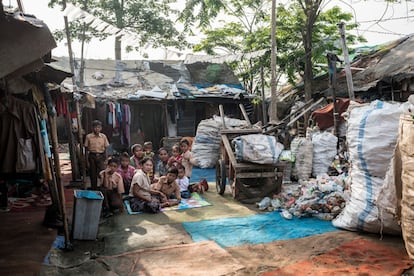 A la entrada de Ciketingudik, mujeres y niños de la pequeña comunidad de recicladores de basura originarios de Indramayu, compuesta por un grupo de familias emparentadas, se sientan en el patio situado en el centro de sus chabolas, donde almacenan y seleccionan las bolsas de basura. Todos los niños han nacido con ayuda de Mak Muji.
