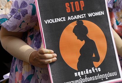 Una trabajadora enseña un cartel en el que aparece una mujer embarazada bajo el lema 'Fin a la violencia contra las mujeres', en una manifestación durante el Día Internacional de la Mujer en Bangkok (Tailandia). 