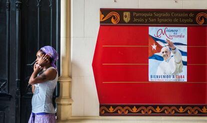 Una mujer y un cartel que anuncia la llegada del Papa en una iglesia de La Habana.