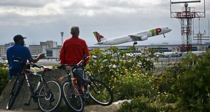 Dos hombres observan el despegue de un avi&oacute;n de TAP en Lisboa.