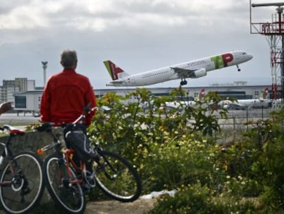 Dos hombres observan el despegue de un avi&oacute;n de TAP en Lisboa.